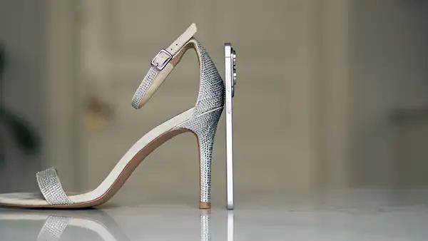 En Samsung Galaxy S25 Edge stilt opp sammen med en høyhælet sko, viser at telefonen er veldig slank