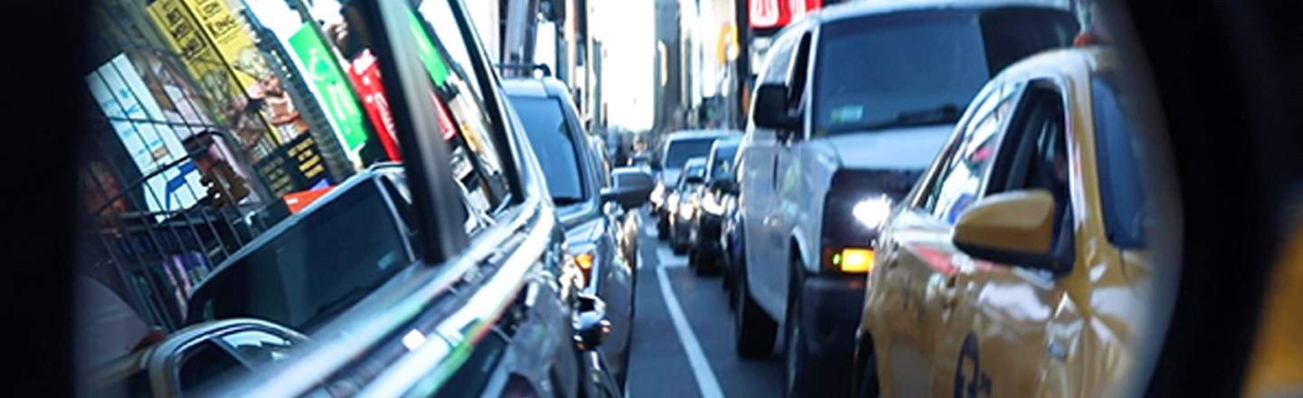 Bilde av et lyskryss i New York City med en fotgjengerovergang og mye trafikk. Smartby.